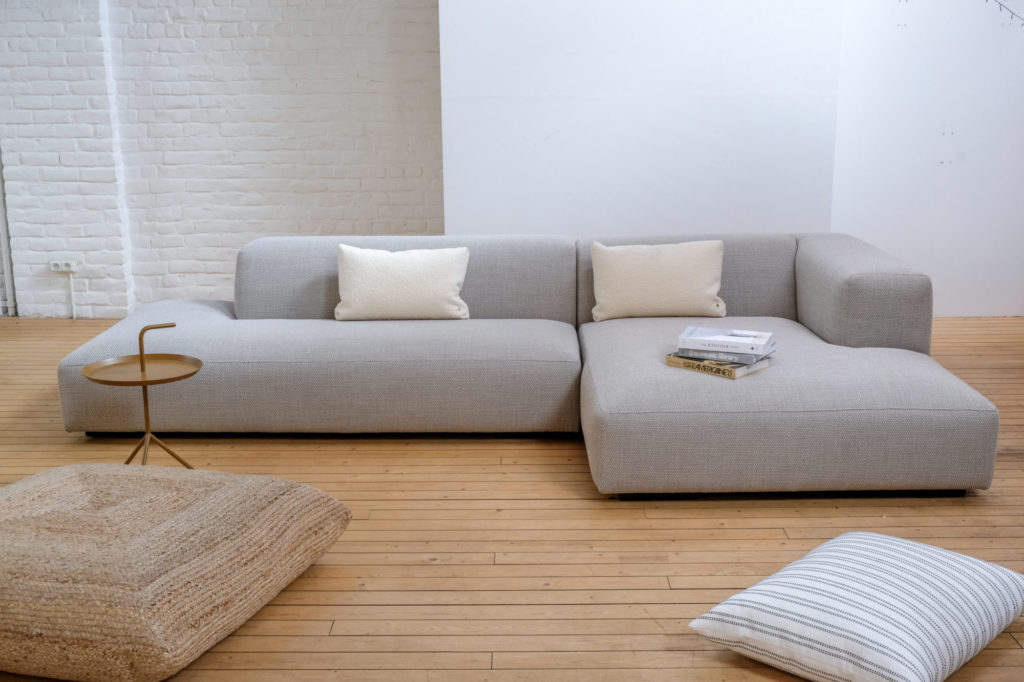 canapé d'angle Robin de Koozo avec deux coussins blancs dans l'espace salon du showroom de quatuor.