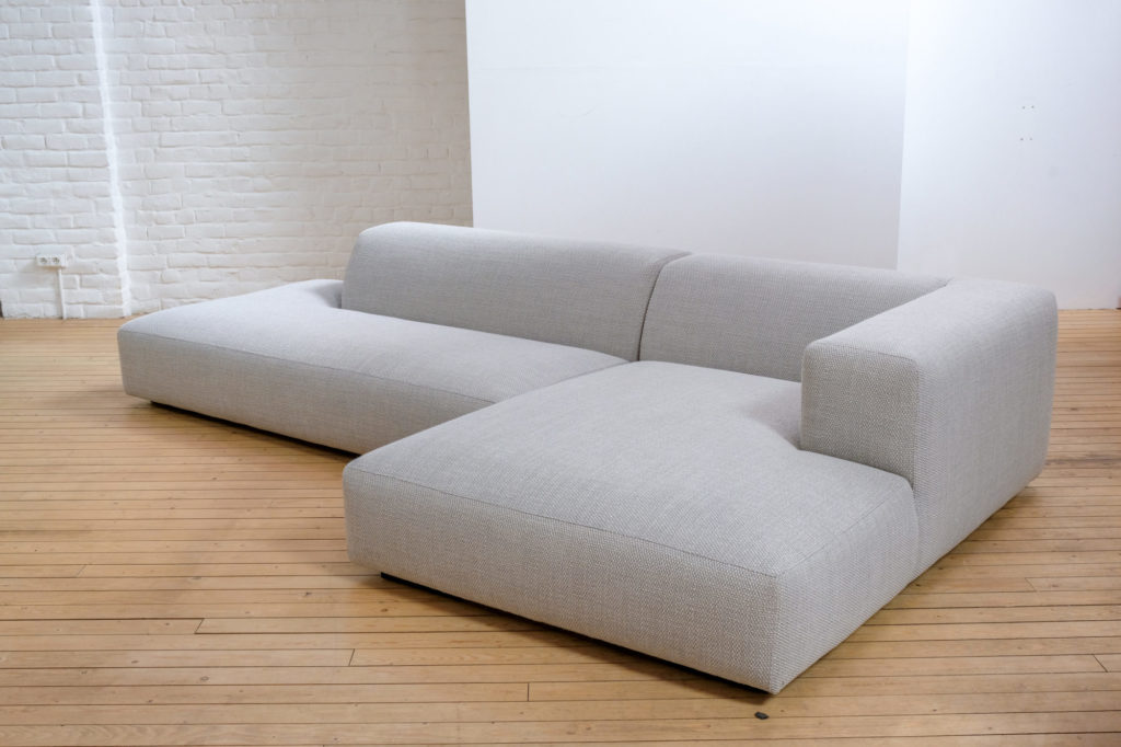 Un canapé sectionnel gris posé sur un plancher en bois.