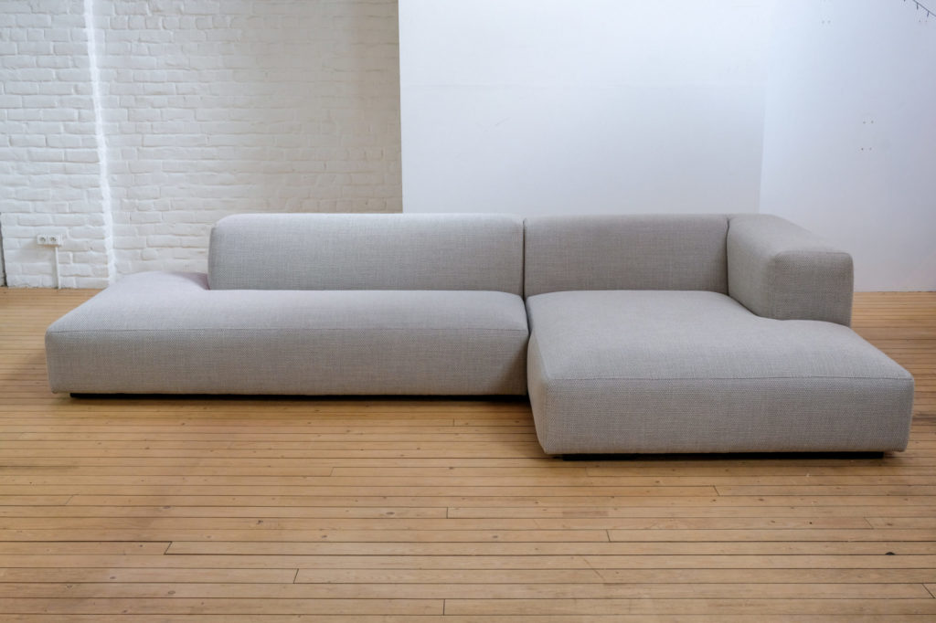 Un canapé sectionnel gris posé sur un plancher en bois.