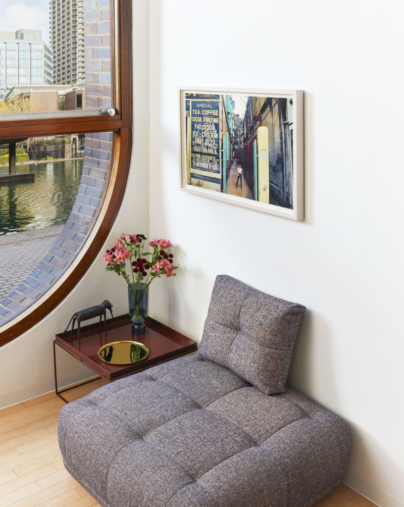 Pouf Quilton ottoman en tissu ou cuir de la marque Hay dans un coin de salon a cote d'une fenetre avec table basse avec un pot de fleur