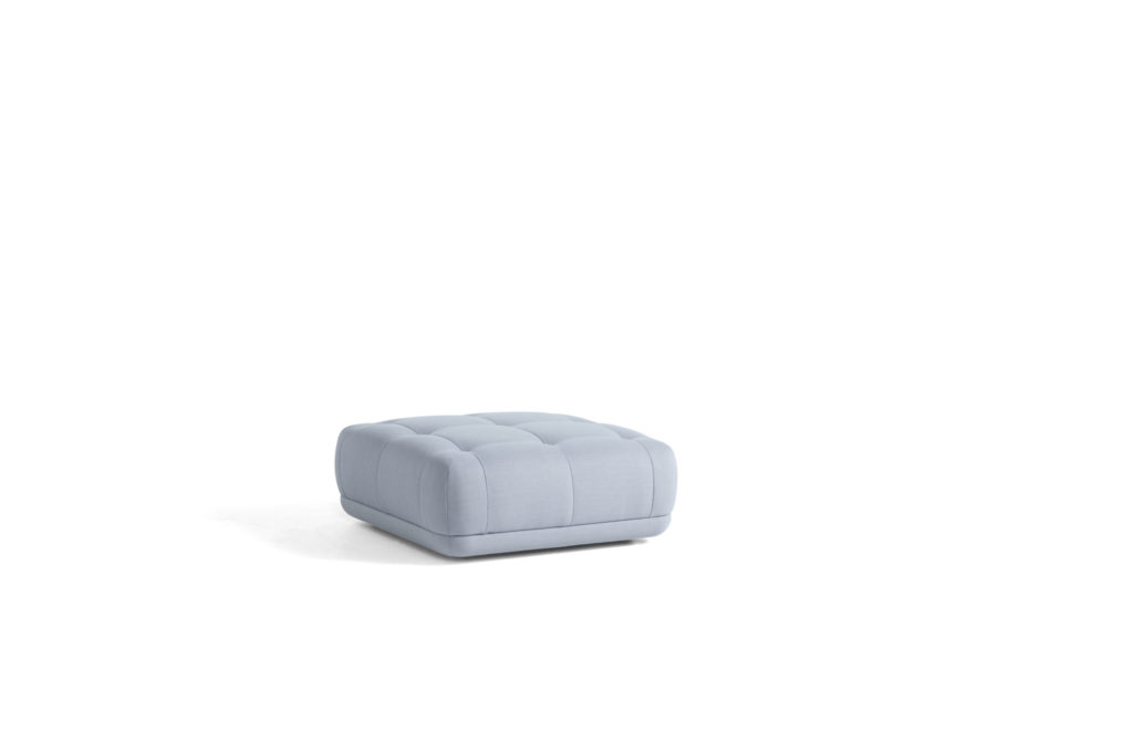 Un petit pouf Pouf Quilton bleu sur fond blanc est aussi appelé pouf.