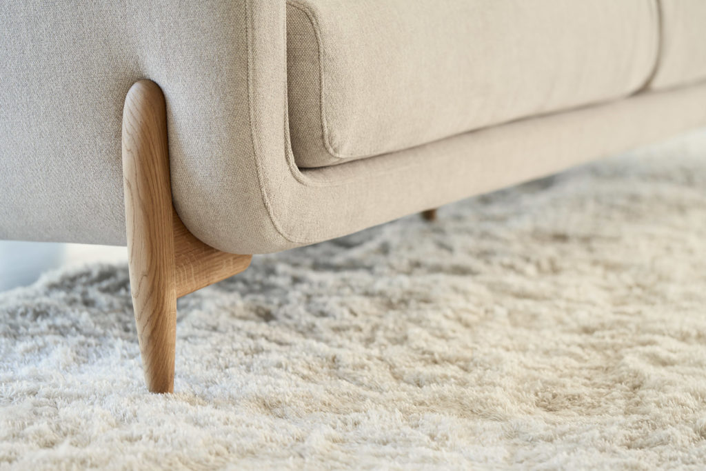 Les pieds d'un Canapé Jenny, 3 places sur un tapis blanc.