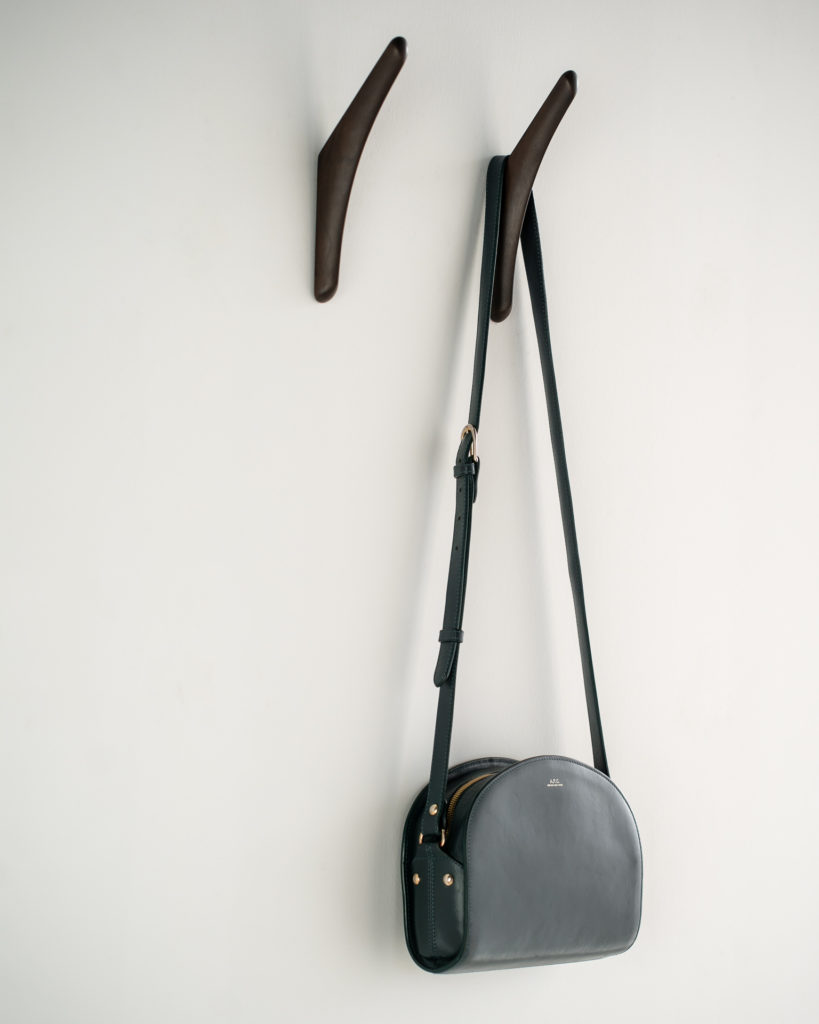 Un sac à main en cuir noir accroché à un mur Set de 2 porte-manteaux en acajou.