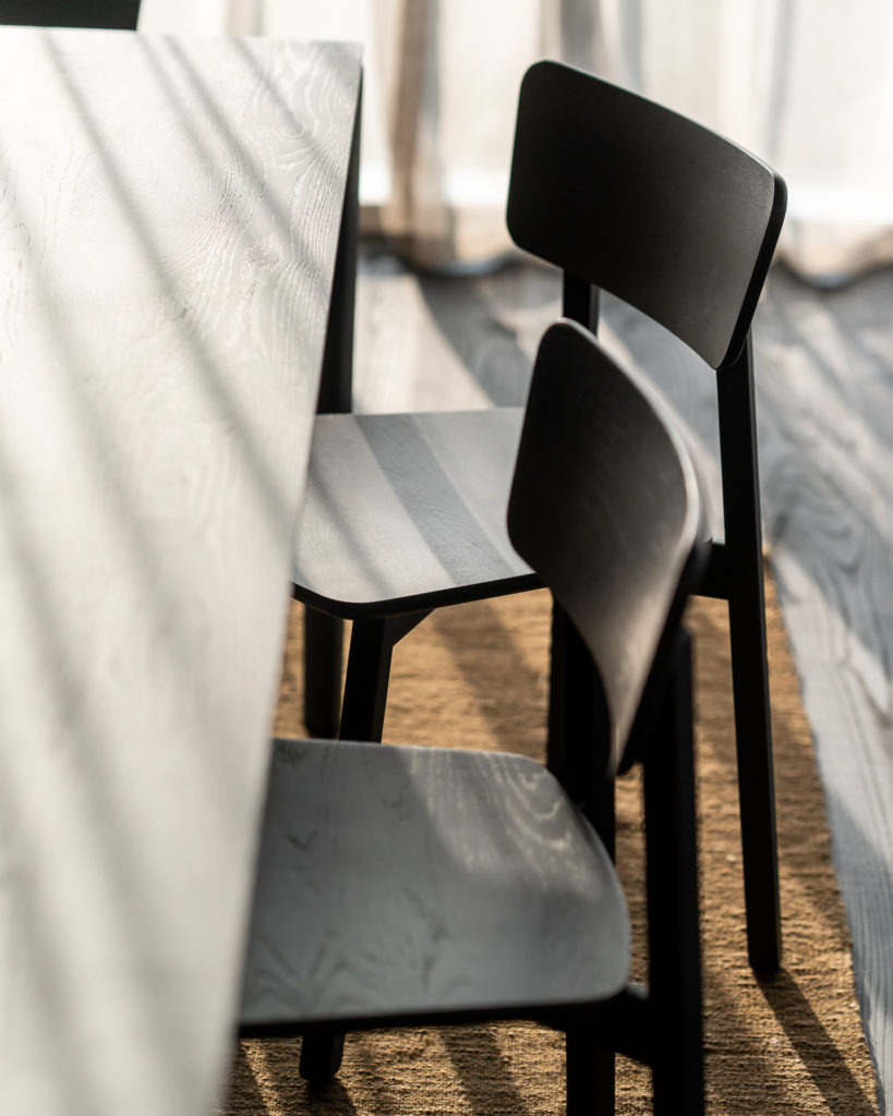 Une table à manger avec une Chaise Casale en chêne noir devant.