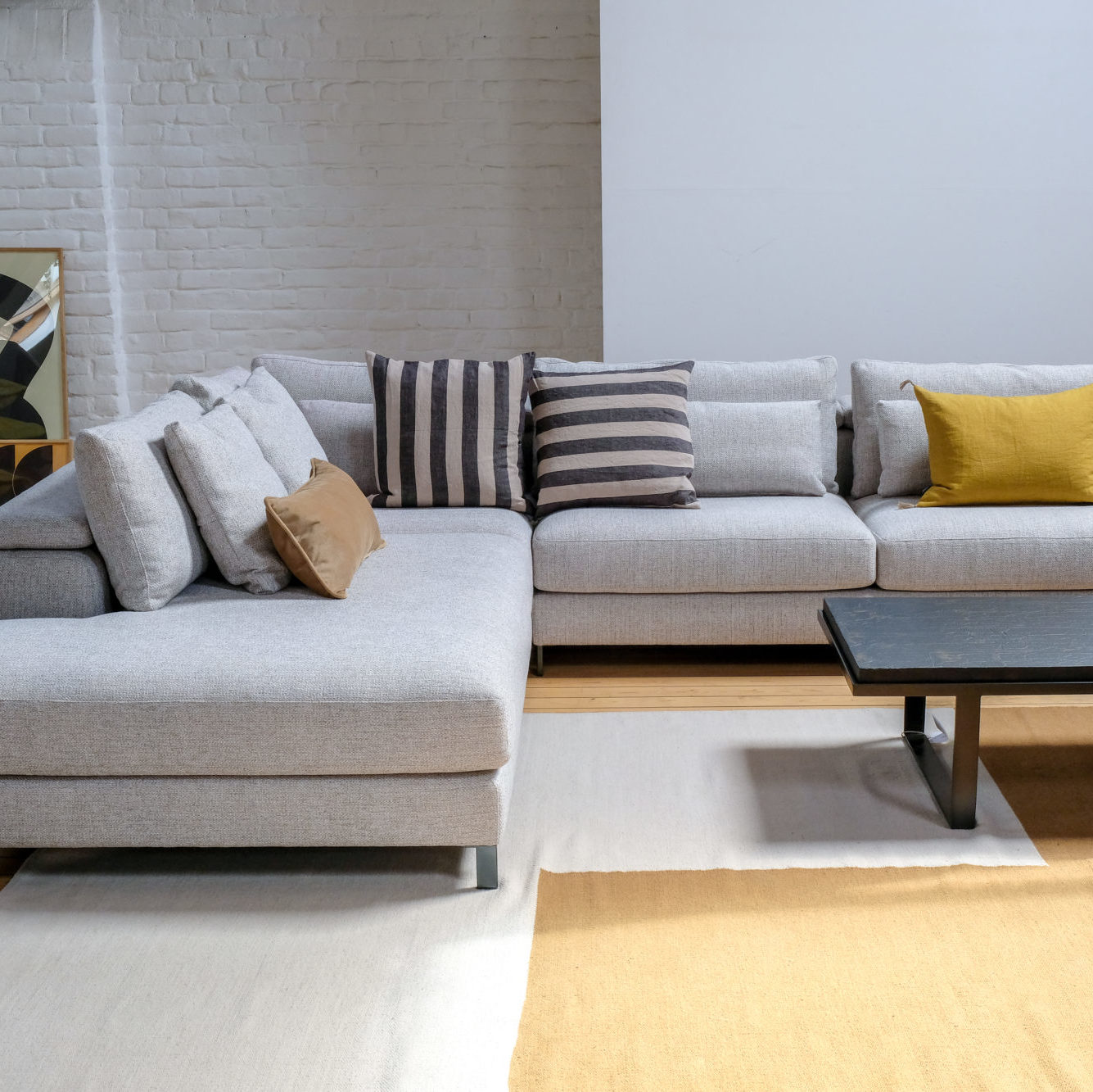 Canapé d'angle horizon d'Olta avec tables basse noire et coussins.