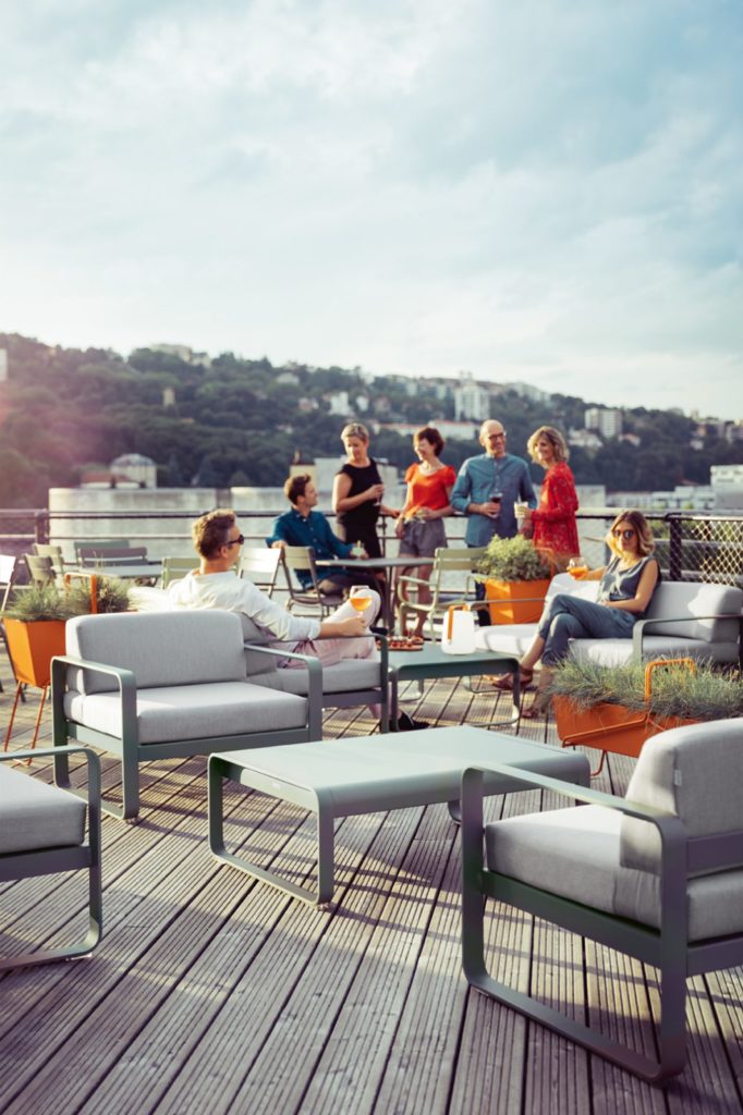 Un groupe de personnes assises sur un Fauteuil Bellevie sur une terrasse en bois.