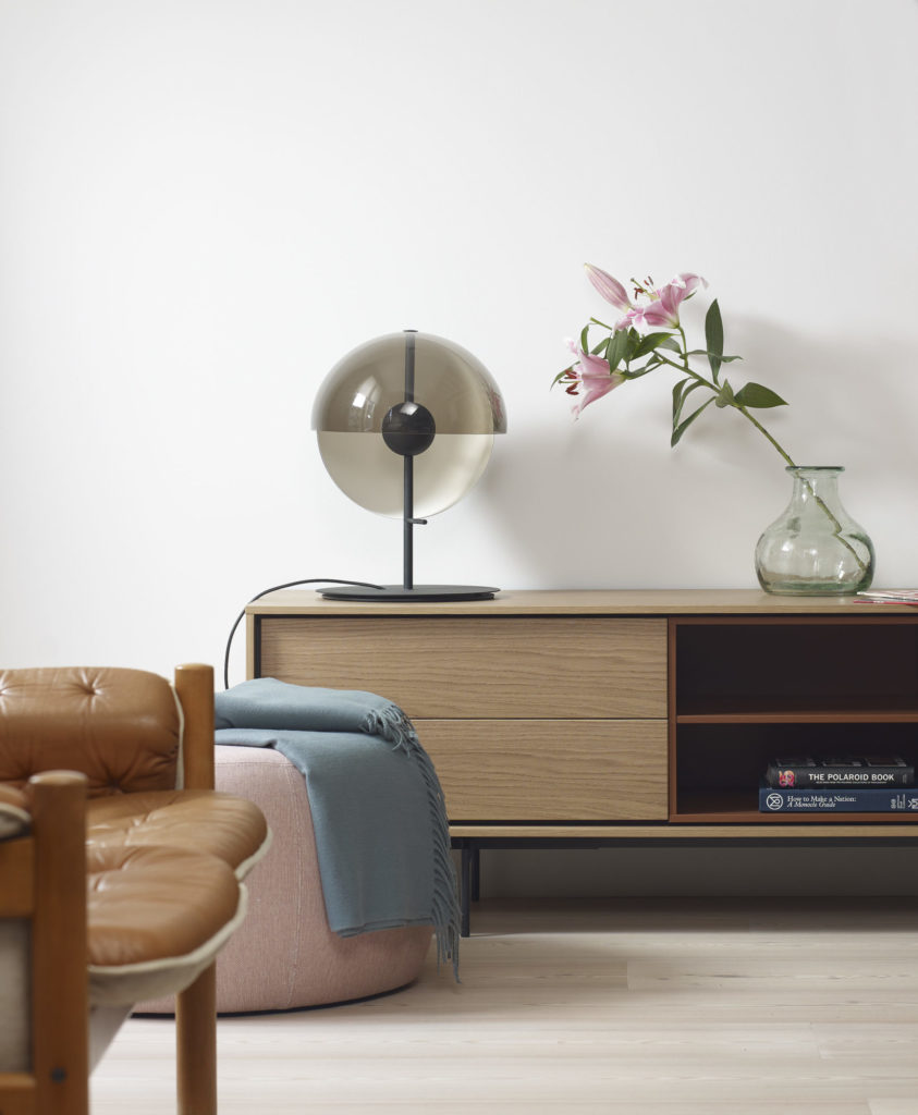 Un séjour avec un Meuble TV modulable Aura, lampe 196 cm, TV et bibliothèque.