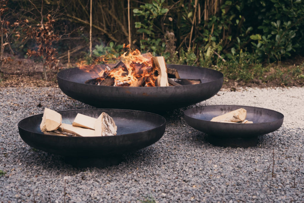 Trois Bol à feu Jesco sur graviers dans un jardin.