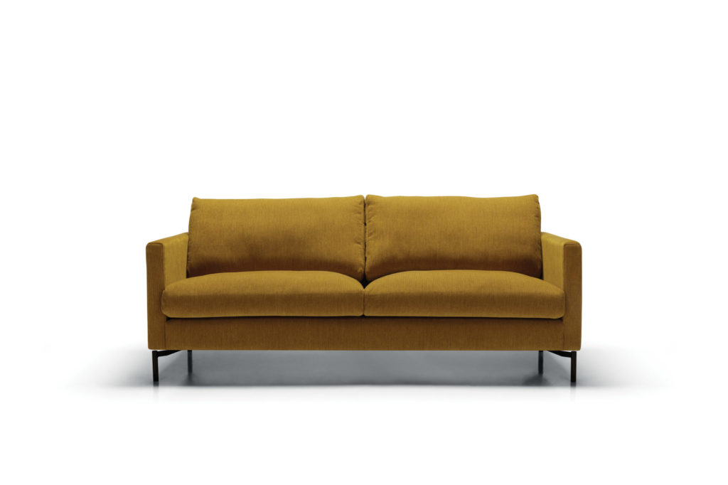 Un canapé jaune avec des pieds noirs sur fond blanc, également connu sous le nom de Canapé Impulse, crée une impulsion accrocheuse.