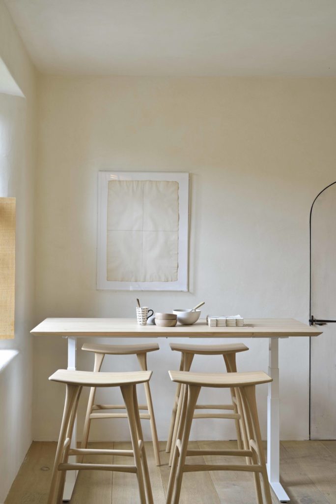 Bureau Bok d’Ethnicraft avec structure en métal blanc, entourée de quatre tabourets hauts Osso en chêne.
