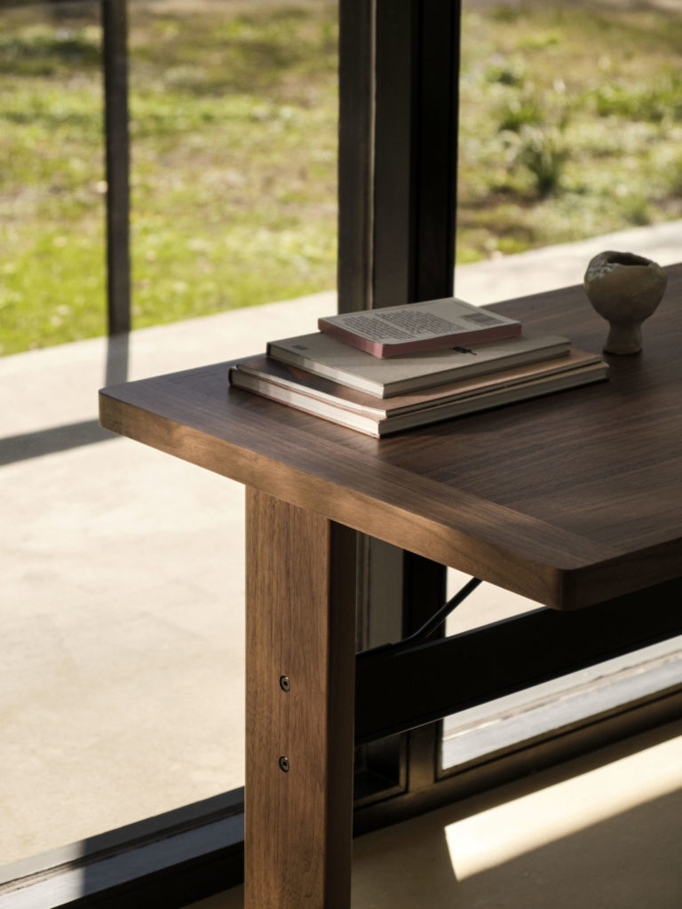 Une table en bois avec un livre dessus devant une fenêtre.