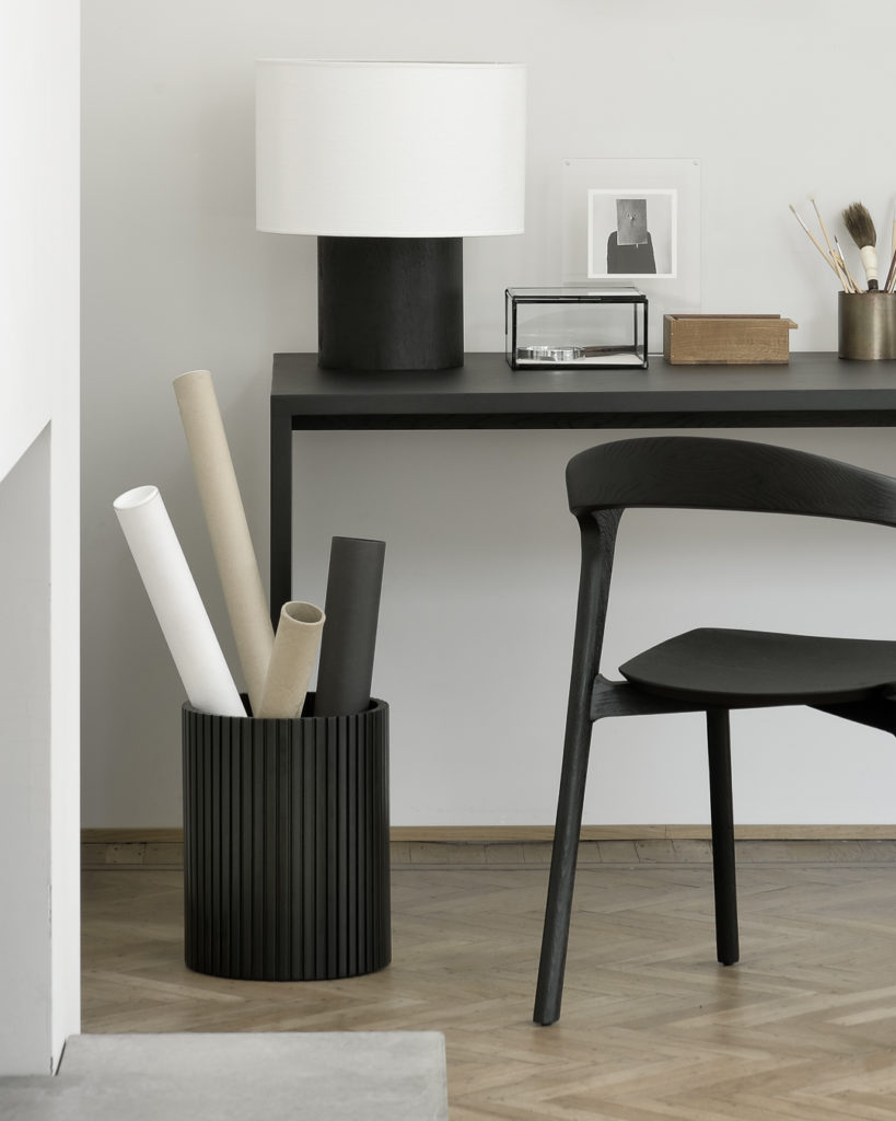 Un bureau noir avec une chaise noire et une lampe, présentant le design Corbeille Roller Max élégant et élégant.
