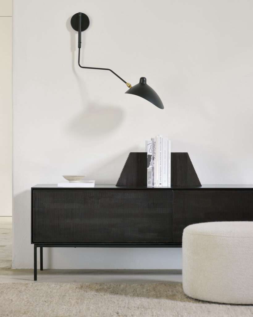 Un salon en noir et blanc avec une lampe Buffet Roller-Max au mur.