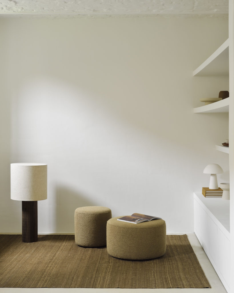 Une chambre blanche avec un tapis diam 40 cm et une lampe, comportant un Pouf Barrow diam 40 cm.