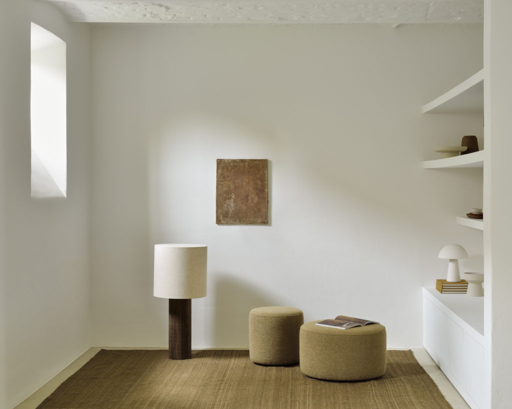 Une pièce aux murs blancs et au sol en bois, dotée d'un Pouf Barrow mesurant 40 cm de diamètre.