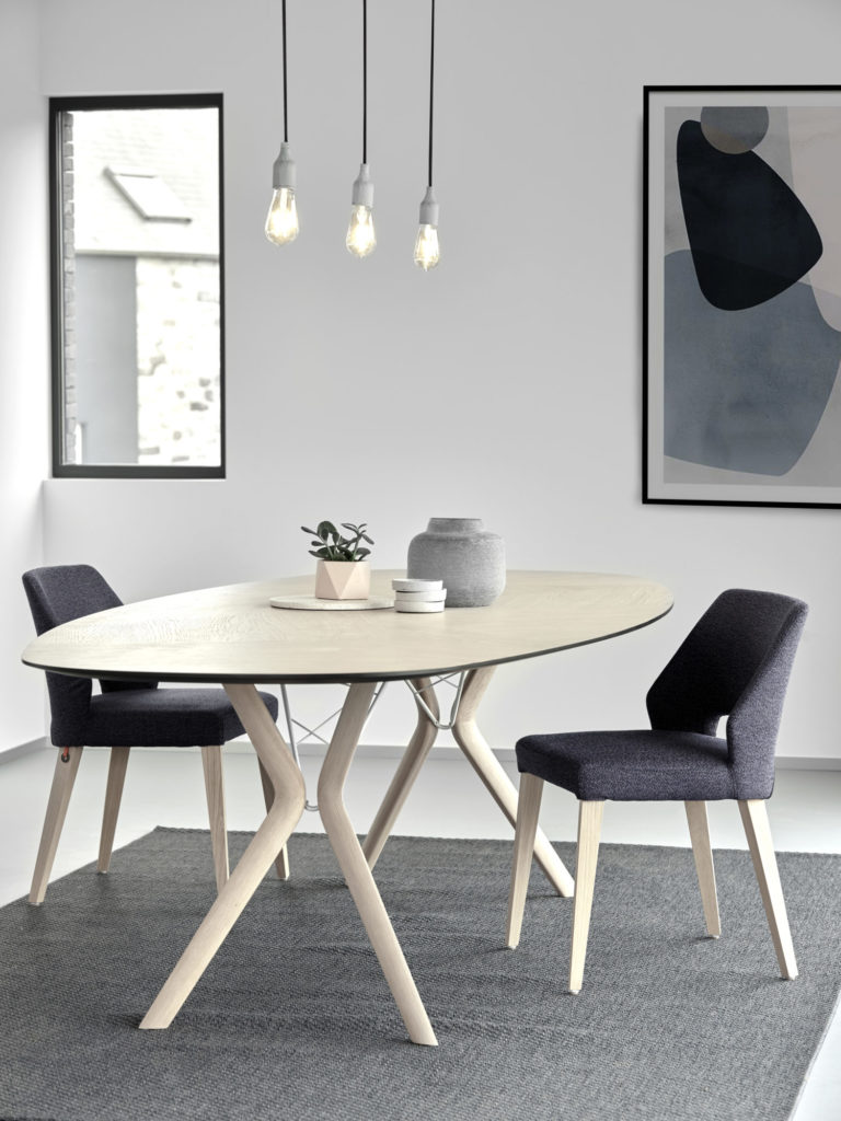 Une table à manger moderne en forme d'Eclipse et des chaises dans une pièce.