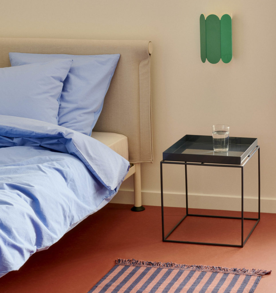 Une chambre stylée d'inspiration Wabi-Sabi mettant en valeur un lit ethnicraft accompagné d'une table de chevet minimaliste.