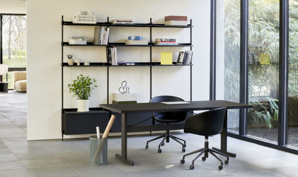Un bureau à domicile avec une table Passerelle noire et des étagères.