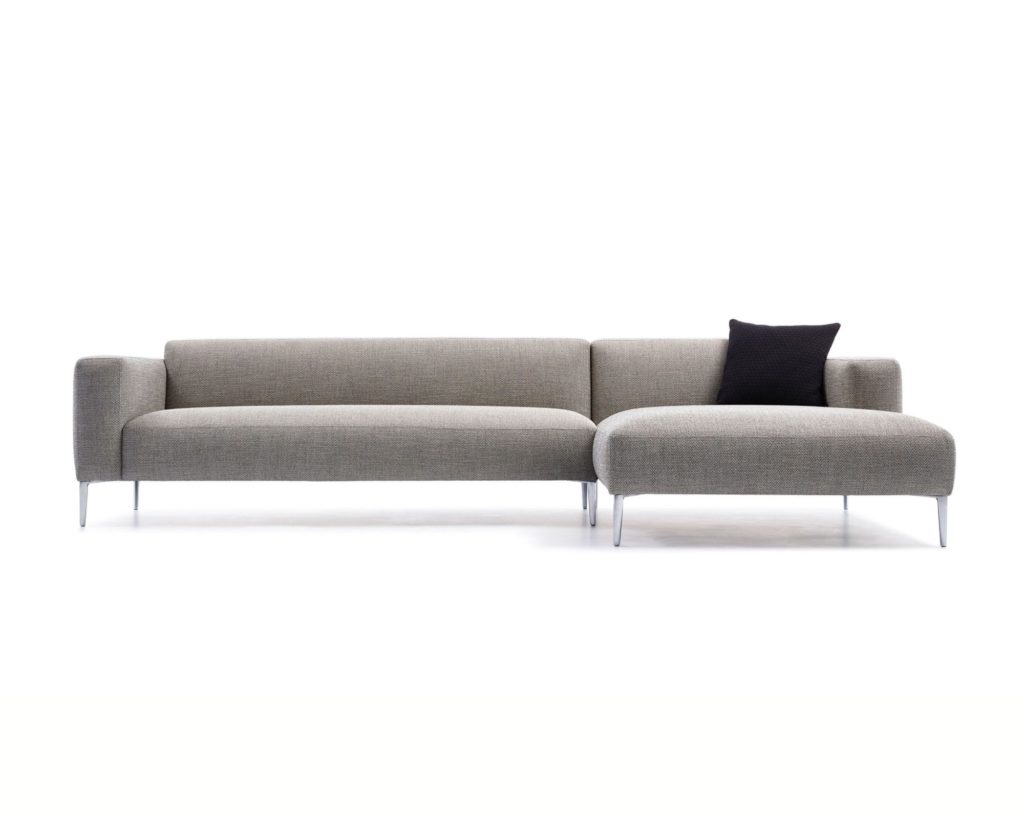 Un canapé sectionnel Canapé Fay gris avec un pouf noir.