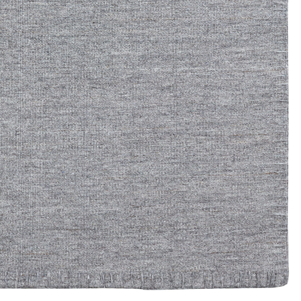 Un tapis Tapis Escape Kelim avec coutures gris sur fond blanc.