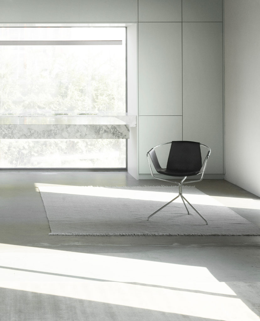 Une pièce blanche avec au milieu une chaise Tapis Escape Kelim avec franges, parfaite pour s'évader.