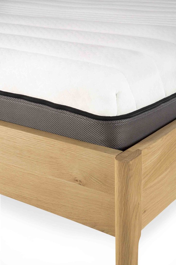 Un cadre de lit ethnicraft avec un Matelas ethnicraft Infinity dessus.