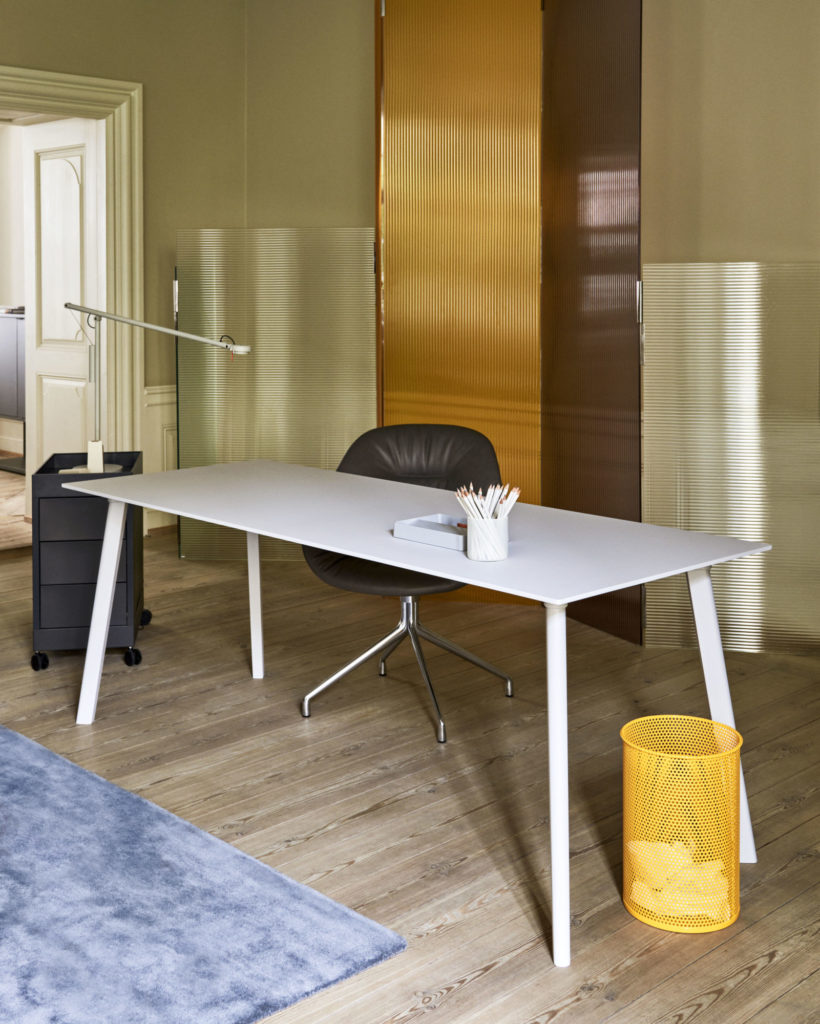 Un tapis jaune complète la Table carrée CPH Deux 210, un bureau blanc qui mesure 75 x 75 cm dans une pièce avec une table carrée.
