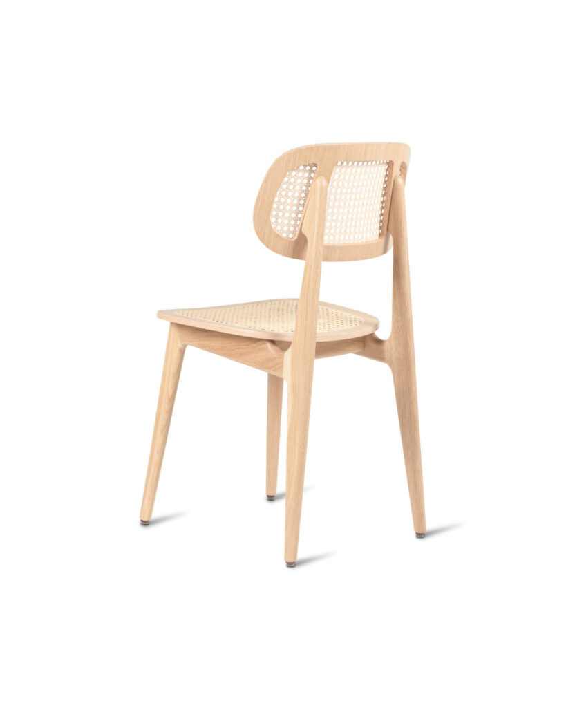 La Chaise Titus est une chaise en bois dotée d'un siège et d'un dossier en rotin finement tressé, légèrement inclinés vers la gauche.