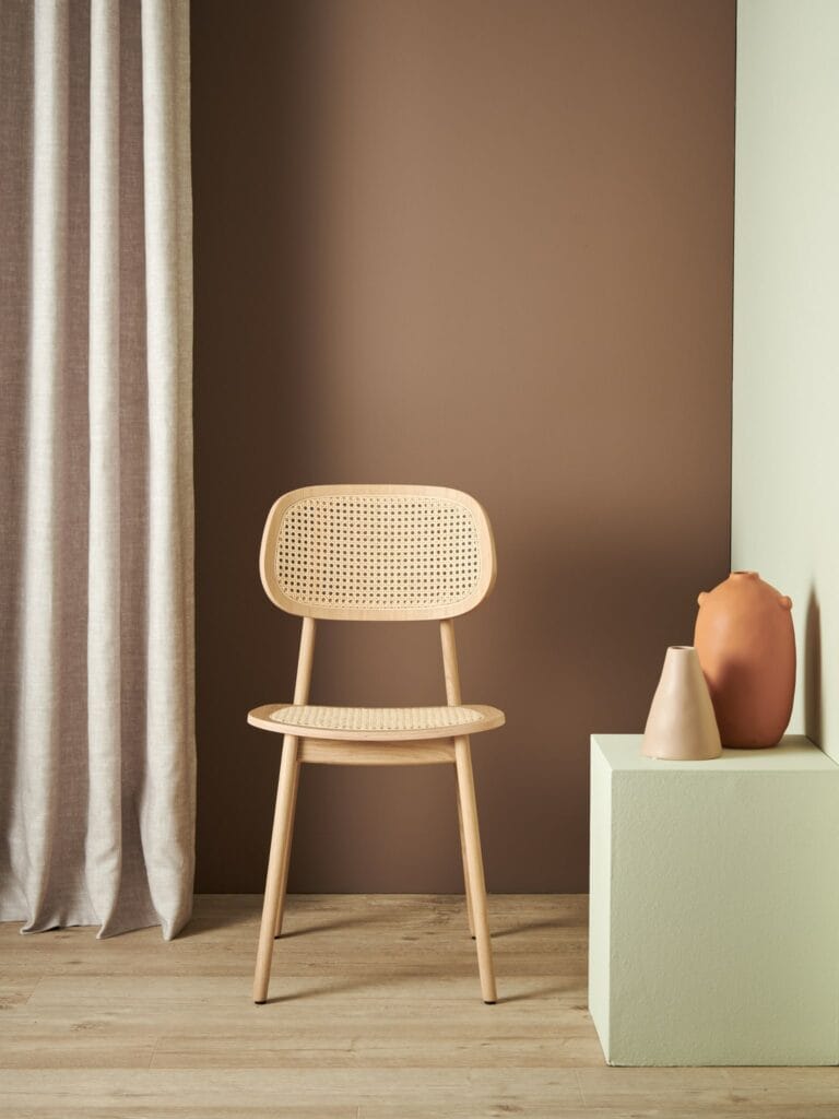 Une chaise Titus devant un mur marron.