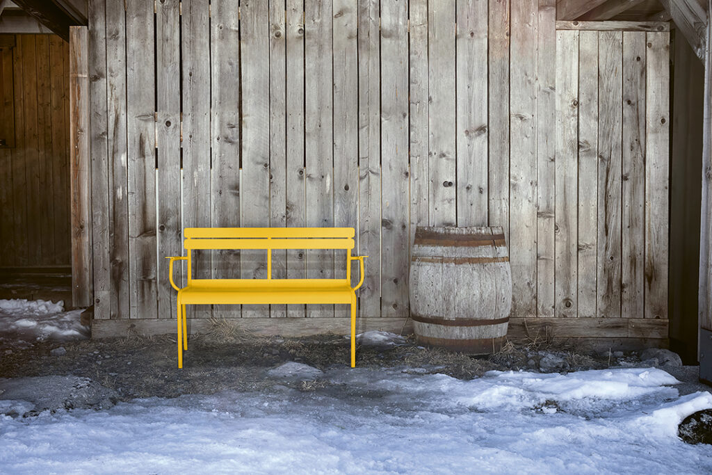 Un Banc Luxembourg avec accoudoirs devant un bâtiment en bois à Luxembourg.