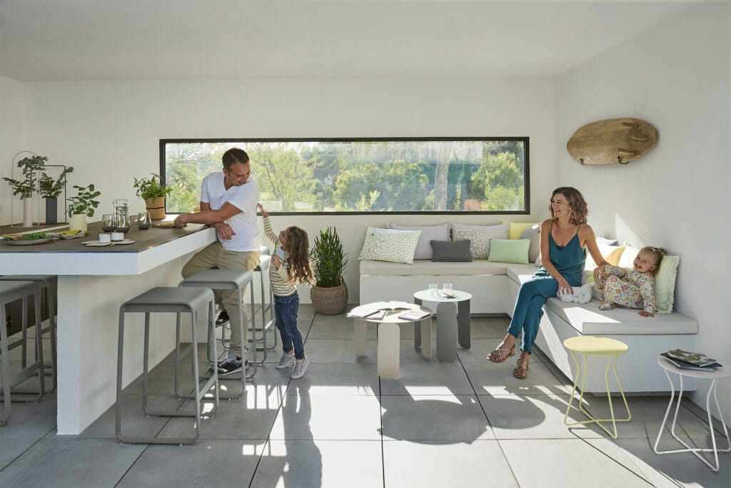 Une famille est assise dans un salon avec un tabouret haut Bellevie et des chaises.
