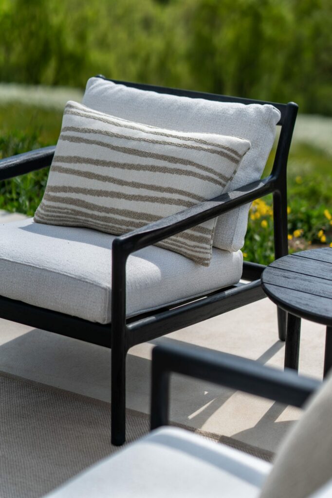 Un fauteuil de jardin Jack en teck noir sur un patio.