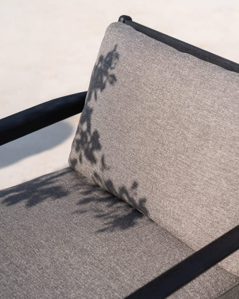 Un fauteuil de jardin Jack en teck noir avec une ombre.