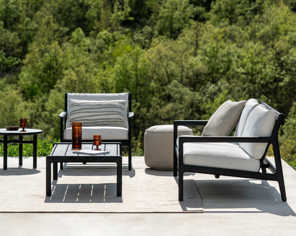 Un mobilier d'extérieur noir et blanc installé sur une terrasse, comprenant un Pouf de jardin Donut.