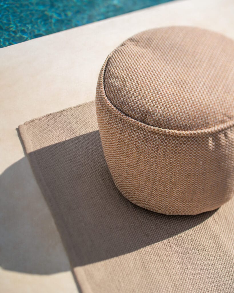 Un Pouf de jardin Donut posé sur un tapis au bord d'une piscine.