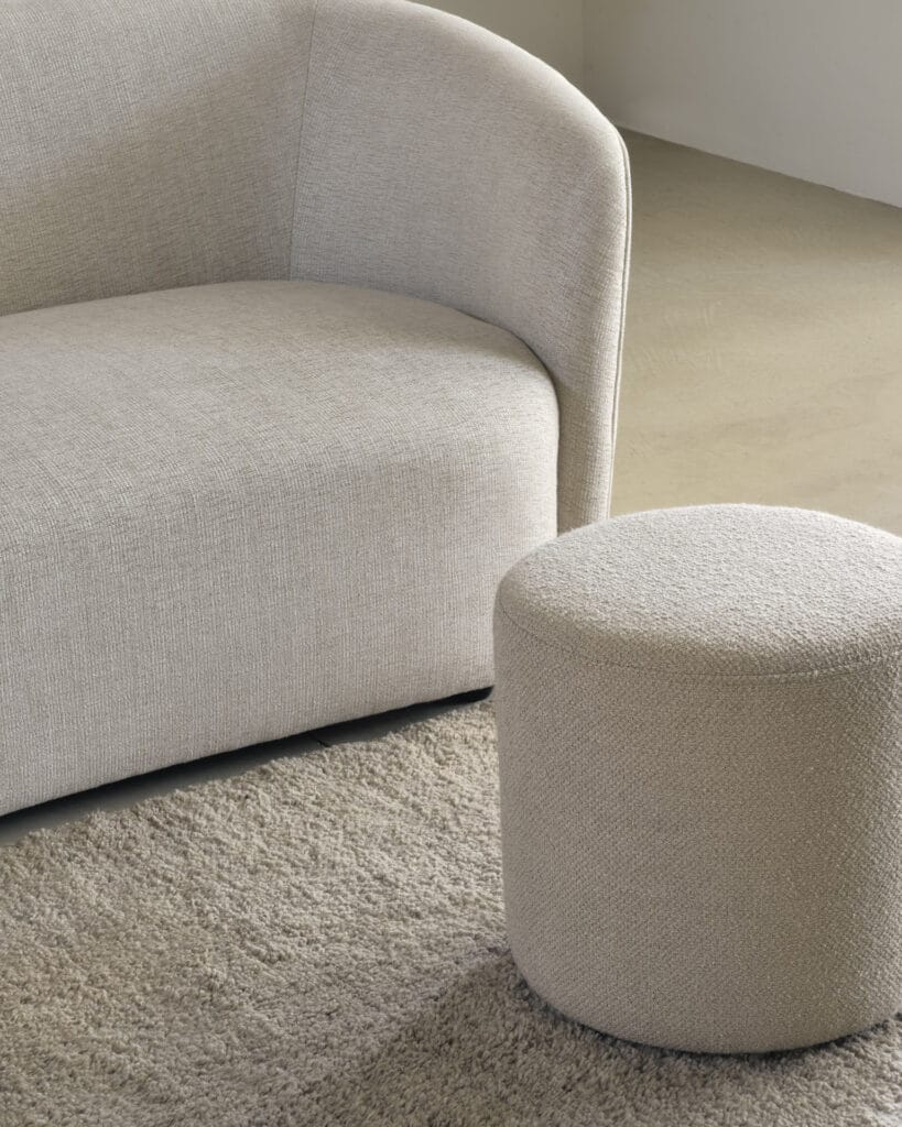 Un canapé et un pouf blancs Tapis Dunes dans une pièce.