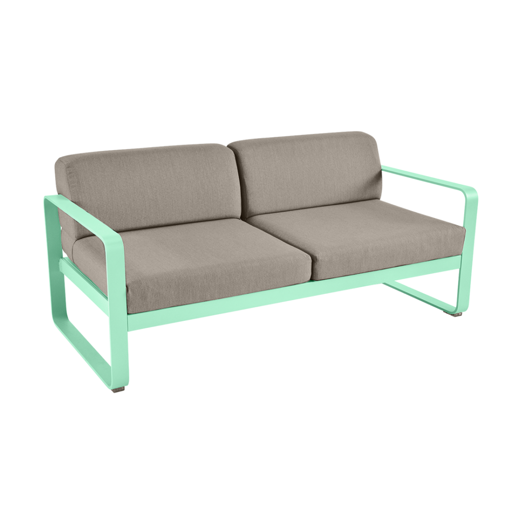Un canapé d'extérieur vert menthe avec un coussin beige.