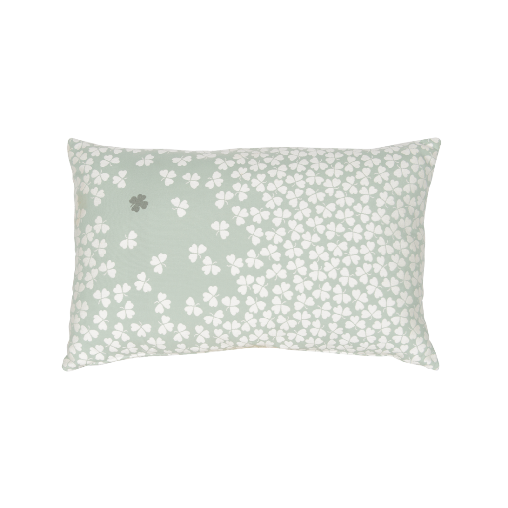 Un coussin aux fleurs blanches sur fond vert clair, inspiré de la beauté délicate du trèfle.