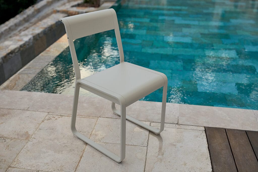 Une chaise blanche, la Chaise V2 Bellevie, posée devant une piscine.