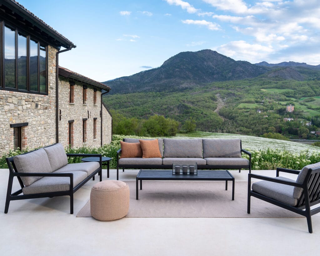 Un Canapé de jardin d'extérieur noir et gris Jack en teck noir - 3 places avec vue montagne dans un écrin de jardin en teck.