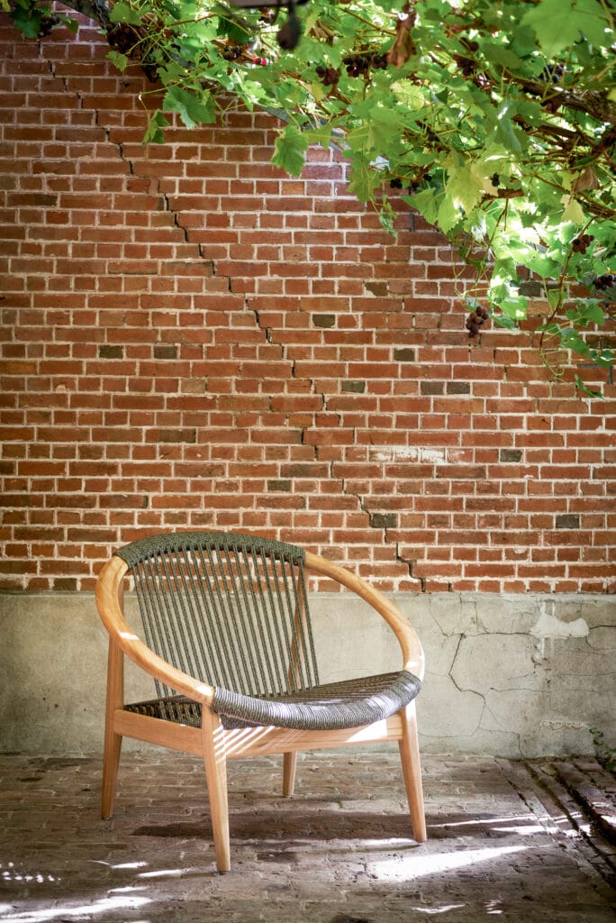 Une chaise longue devant un mur de briques.