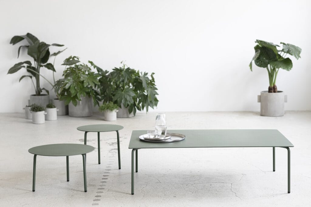 Une table basse August verte et des tabourets dans une pièce avec des plantes.