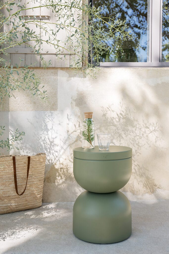 Une table d'appoint Tabouret Piapolo à côté d'une plante.