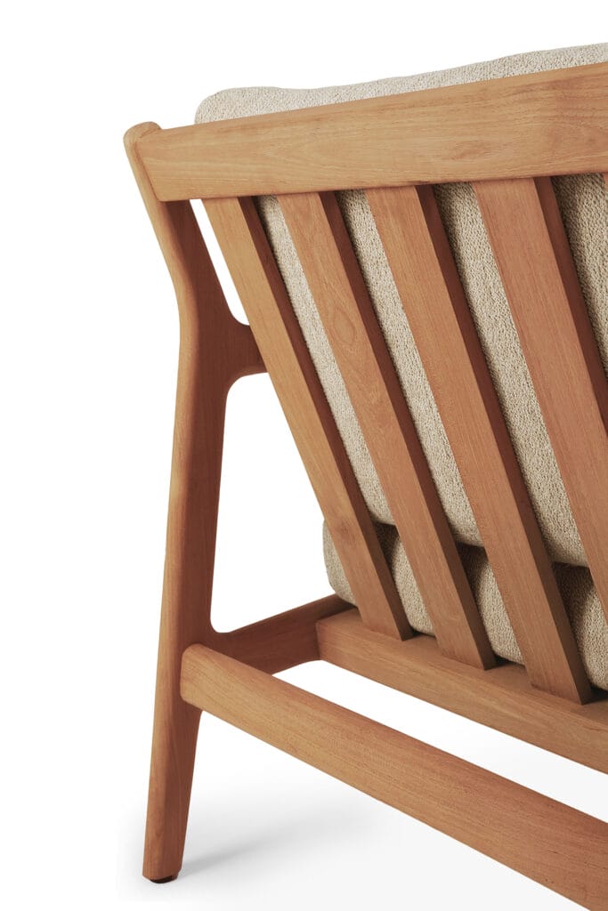 Le dossier en teck naturel d'une chaise en bois avec un coussin.