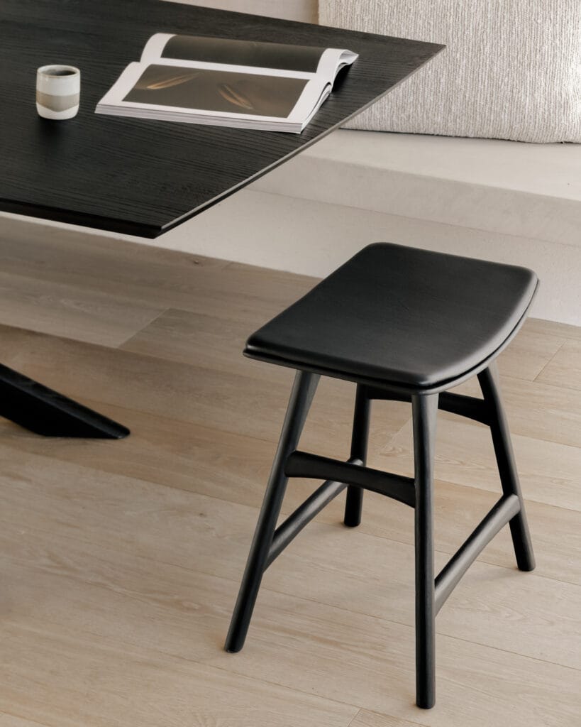 Un tabouret Osso noir est placé à côté d'une table.