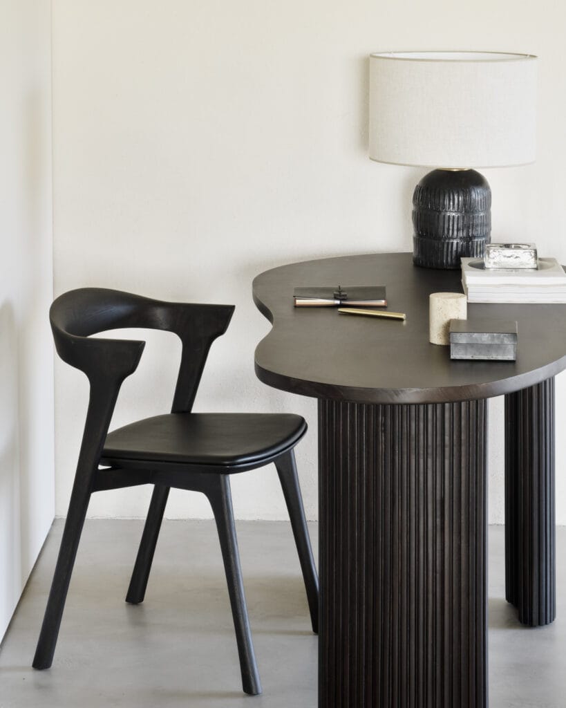 Un Bureau Boomerang en forme d'acajou avec une chaise noire et une lampe.