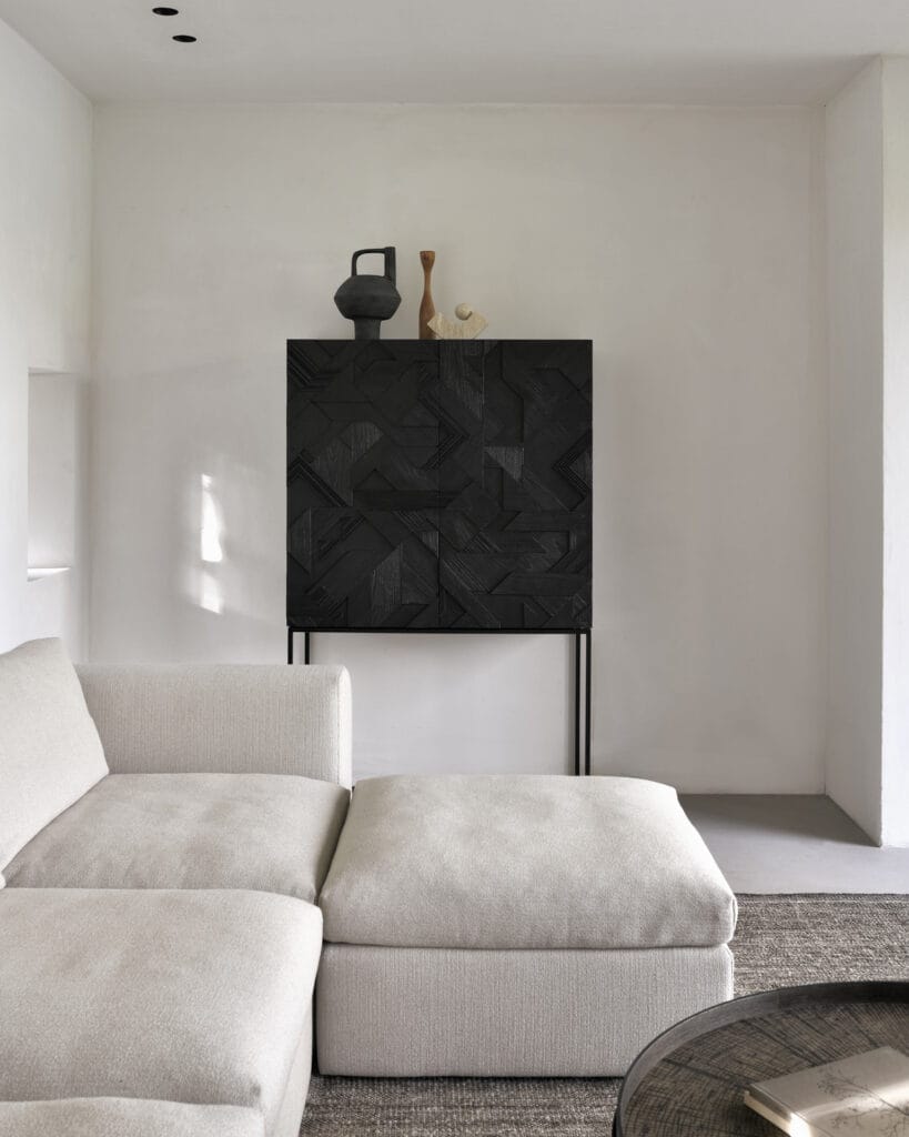 Un salon Armoire Graphic en teck noir avec un canapé blanc et une armoire noire.