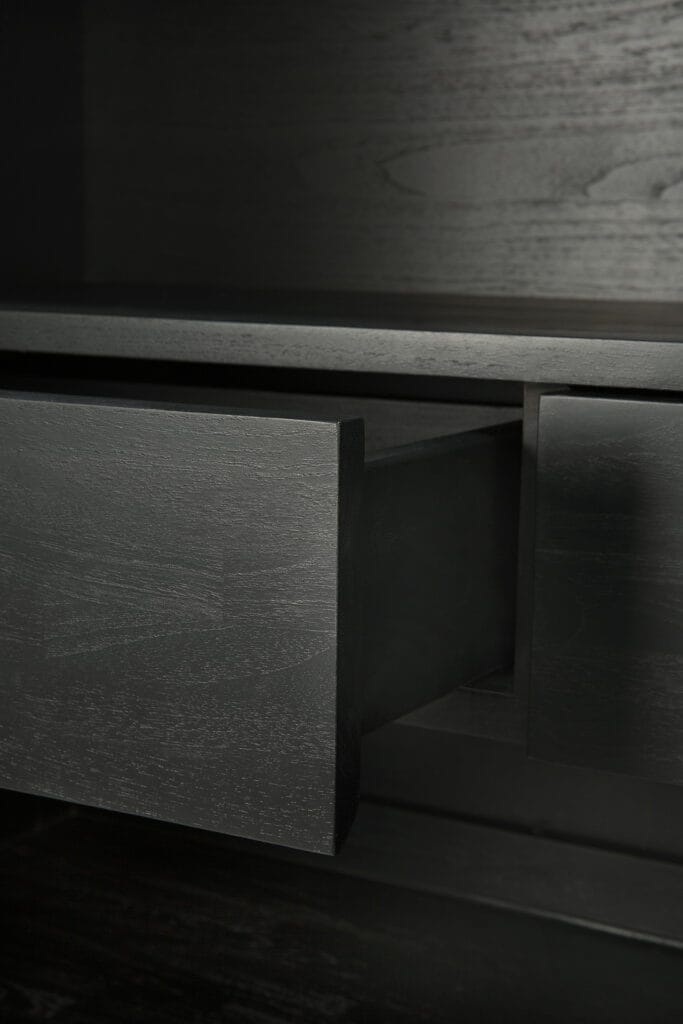 Un gros plan d'un tiroir Armoire Graphic en teck noir noir dans une pièce sombre.