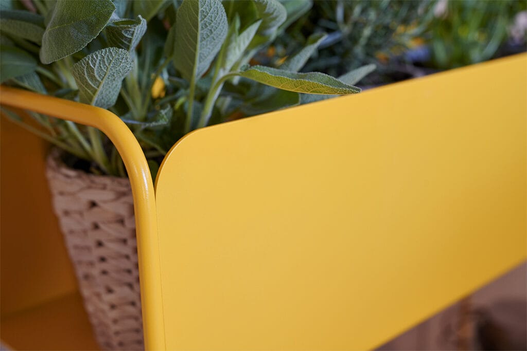 Une jardinière Cache-pot Picolino jaune avec un panier rempli de plantes.