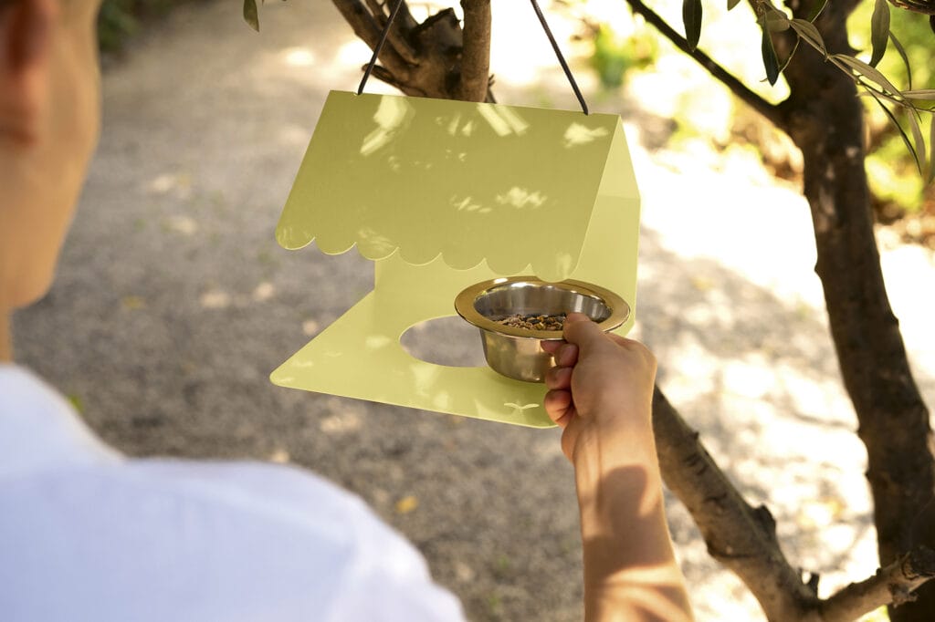 Un Picoti mangeoire à oiseaux tient une mangeoire à oiseaux jaune sur un arbre.